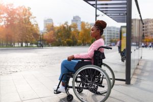Black paraplegic woman in wheelchair waiting on bus stop