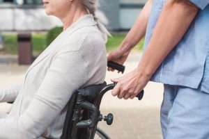 cropped shot of nurse pushing wheelchair with senior woman