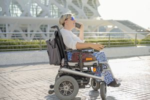 portrait of a smiling woman sitting in an electric wheelchair talking on a mobile phone