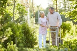 Full length portrait of senior man walking in hospital park with wife